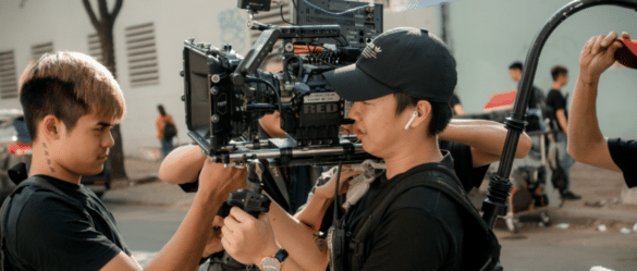 Camera operator holding camera with crew surrounding