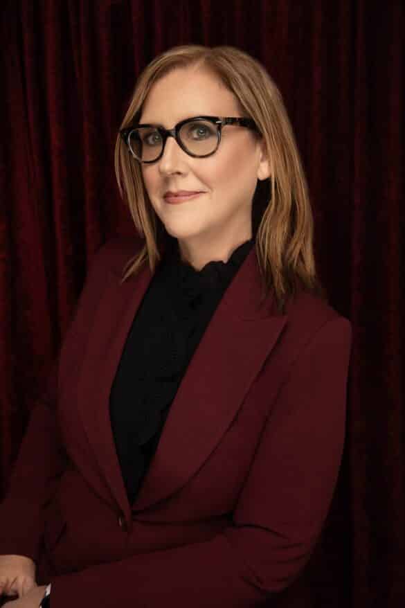 A head shot of author and teacher C.J. Spataro. She wears glasses and a maroon blazer.