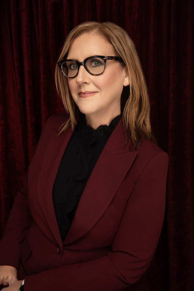 A head shot of author and teacher C.J. Spataro. She wears glasses and a maroon blazer.